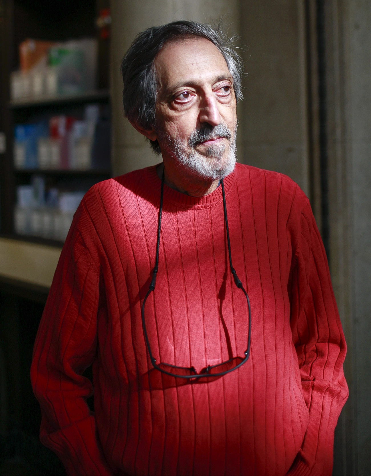 Avi Wigderson stands in a red sweater with sunglasses hanging from his neck.