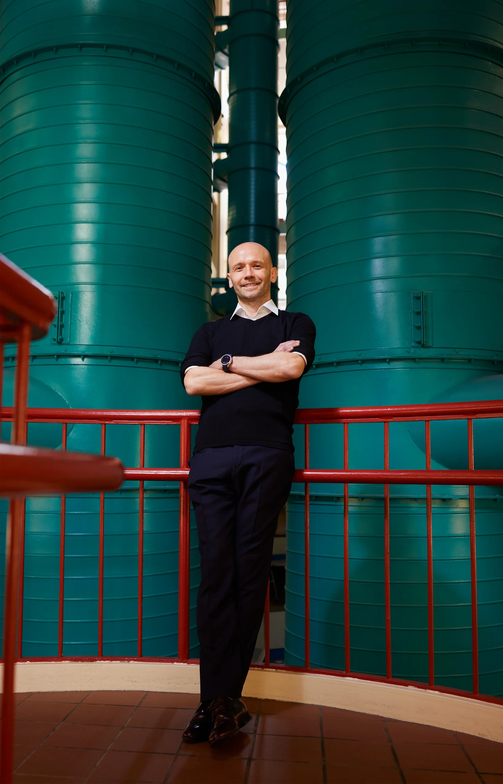 Portrait of a man standing in front of some cylindrical green tanks.