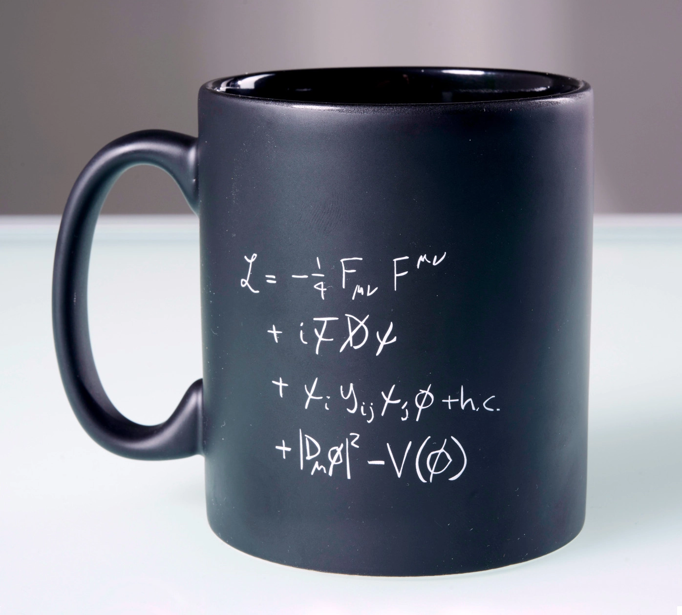 A compact equation is displayed on a black coffee mug.