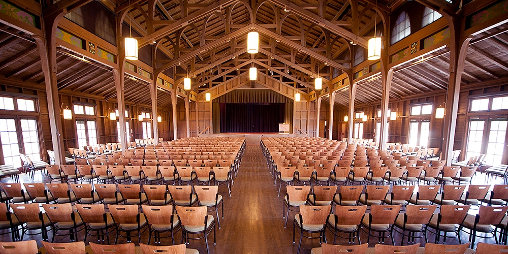 Rows of wooden benches sit inside a wooden structure.