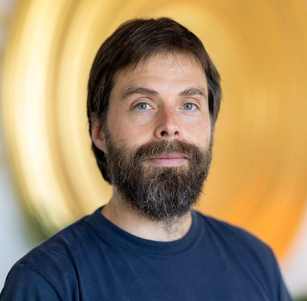 A close-up portrait of a man with a beard.