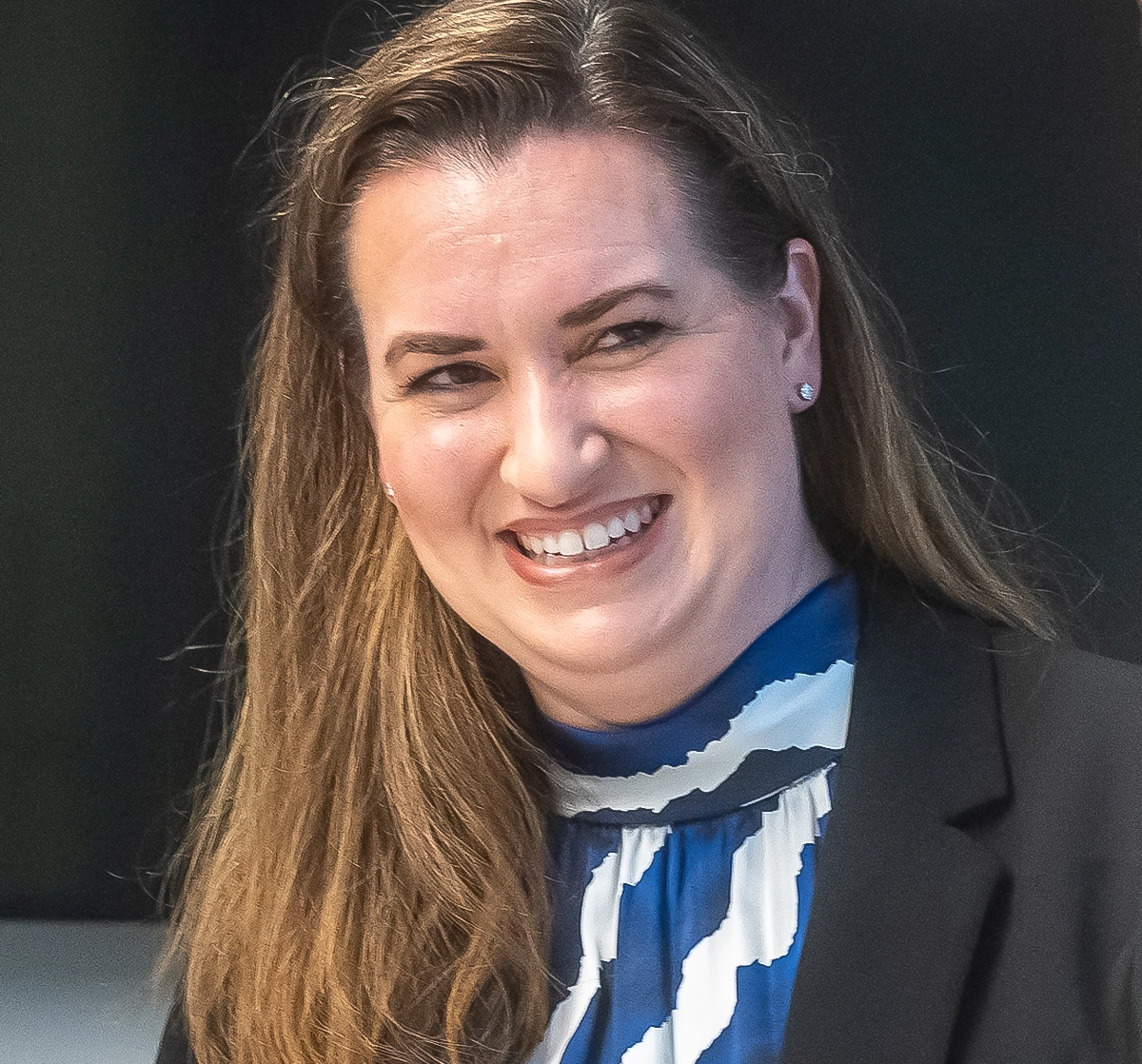 Amanda Randles in a black blazer and blue and white blouse with a black background