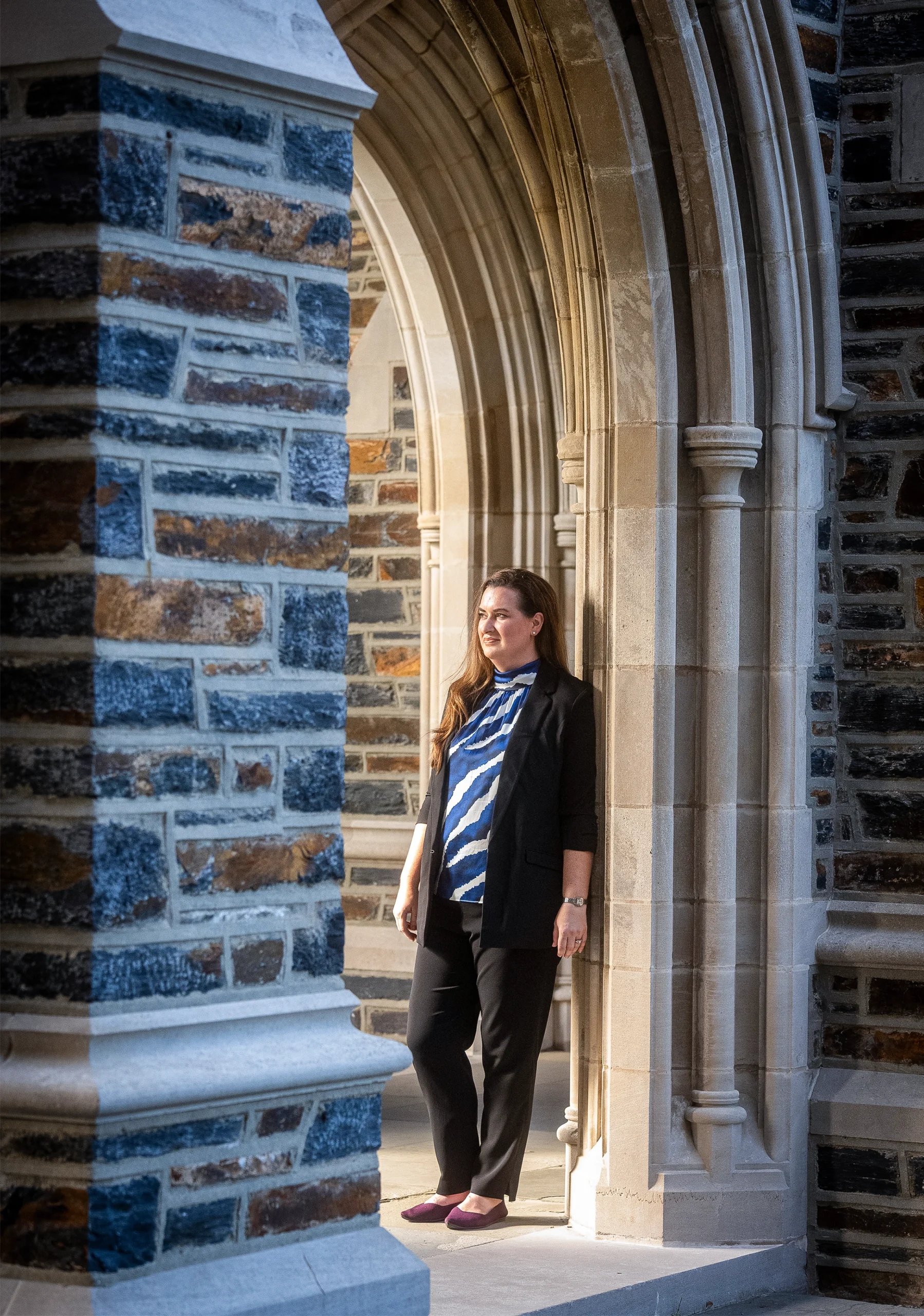 Amanda Randles leans against and archway in a stone wall