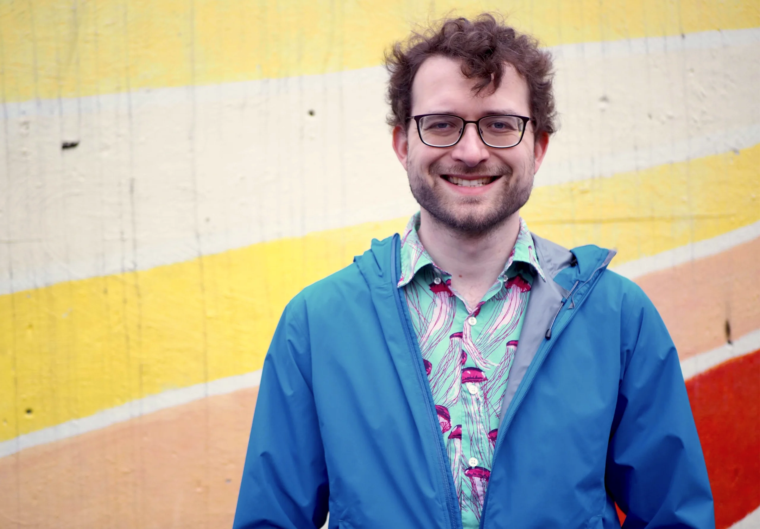 Shawn Ligocki, in a blue-patterned shirt and blue jacket, stands in front of a striped wall.