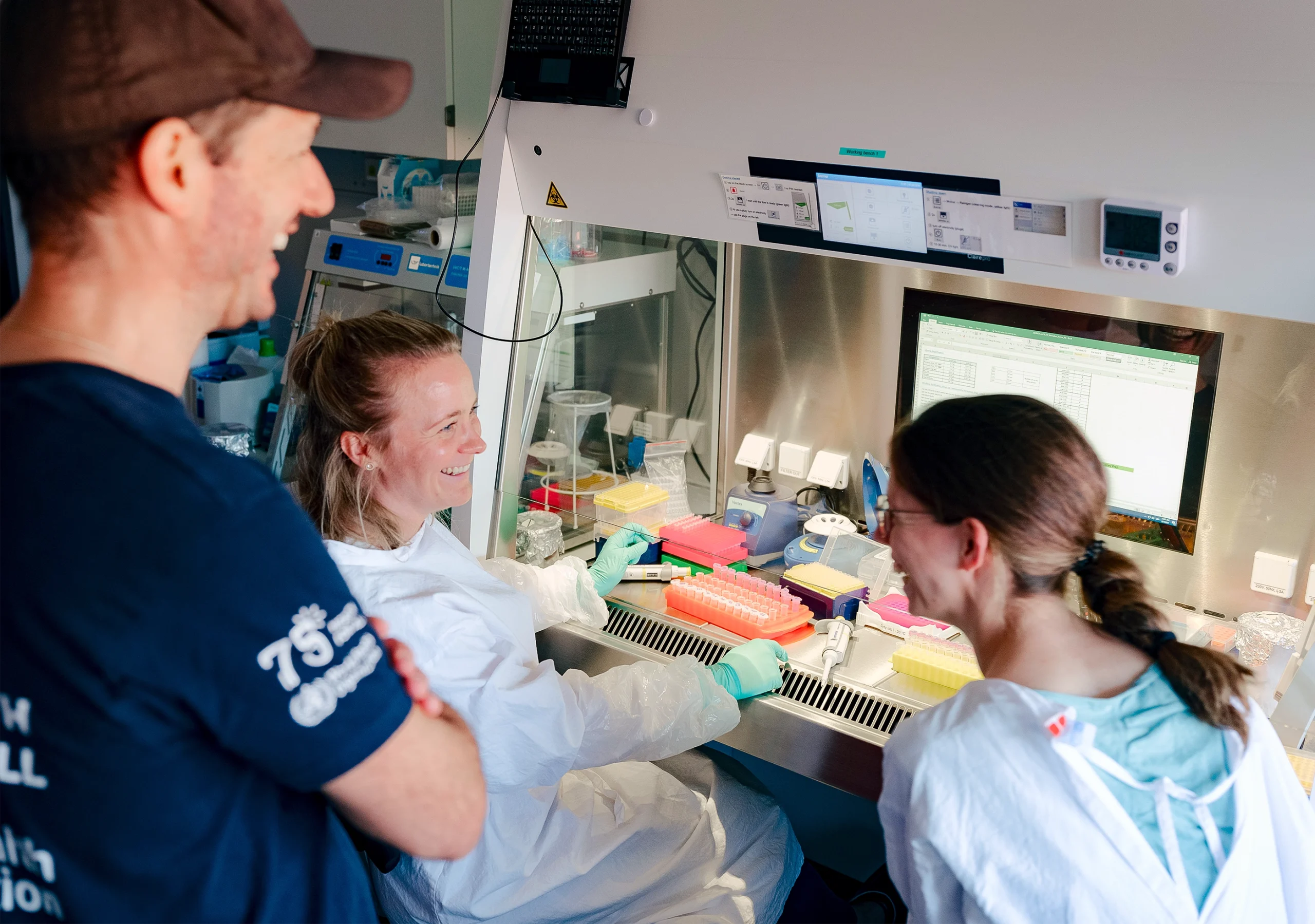 Calvignac-Spencer smiles and laughs with several other scientists in the lab.