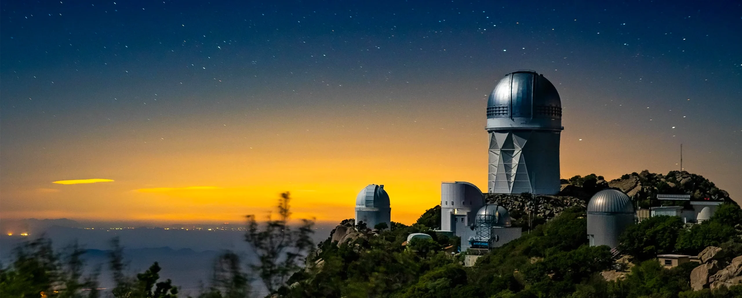 A telescope sitting atop a mountain beneath a starry sky.