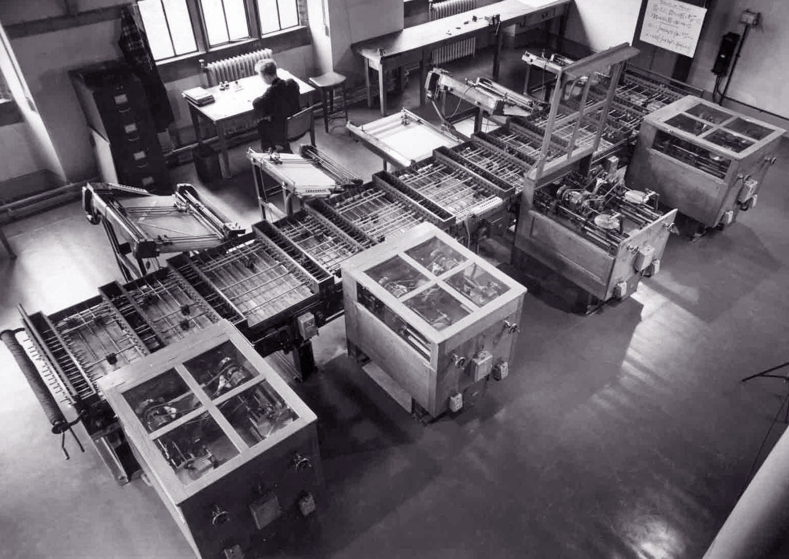 A black-and-white photo of a large machine full of gears and shafts in black and white.