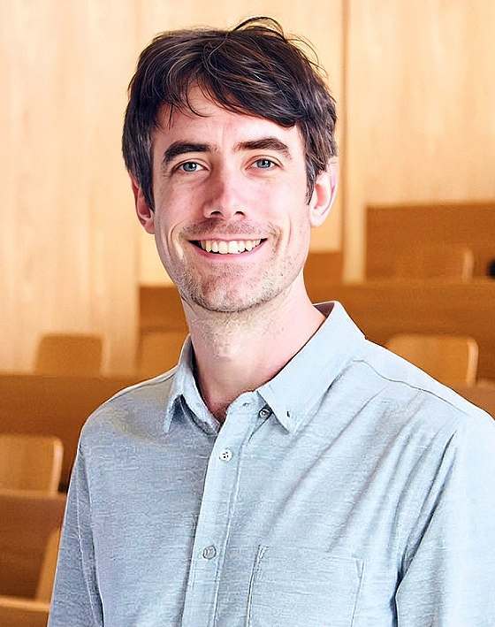 Portrait of a smiling young man in a gray shirt.