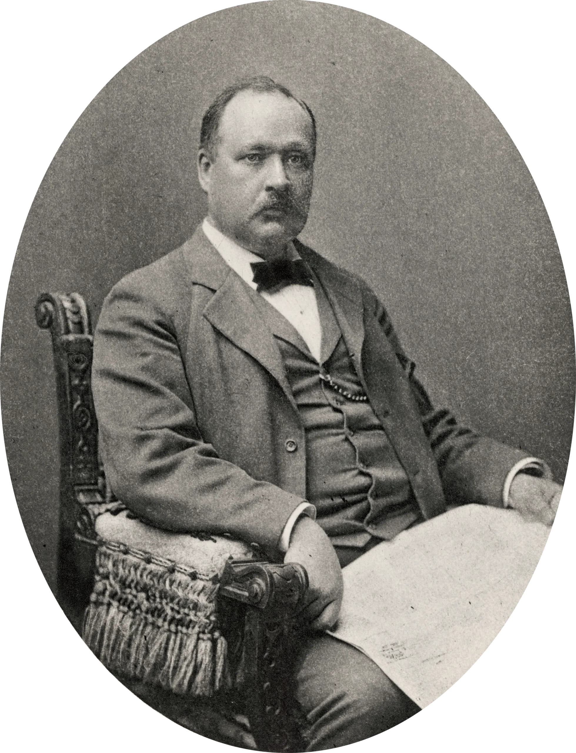 Black-and-white portrait of a serious-looking, heavy-set man in a three-piece suit and bowtie.