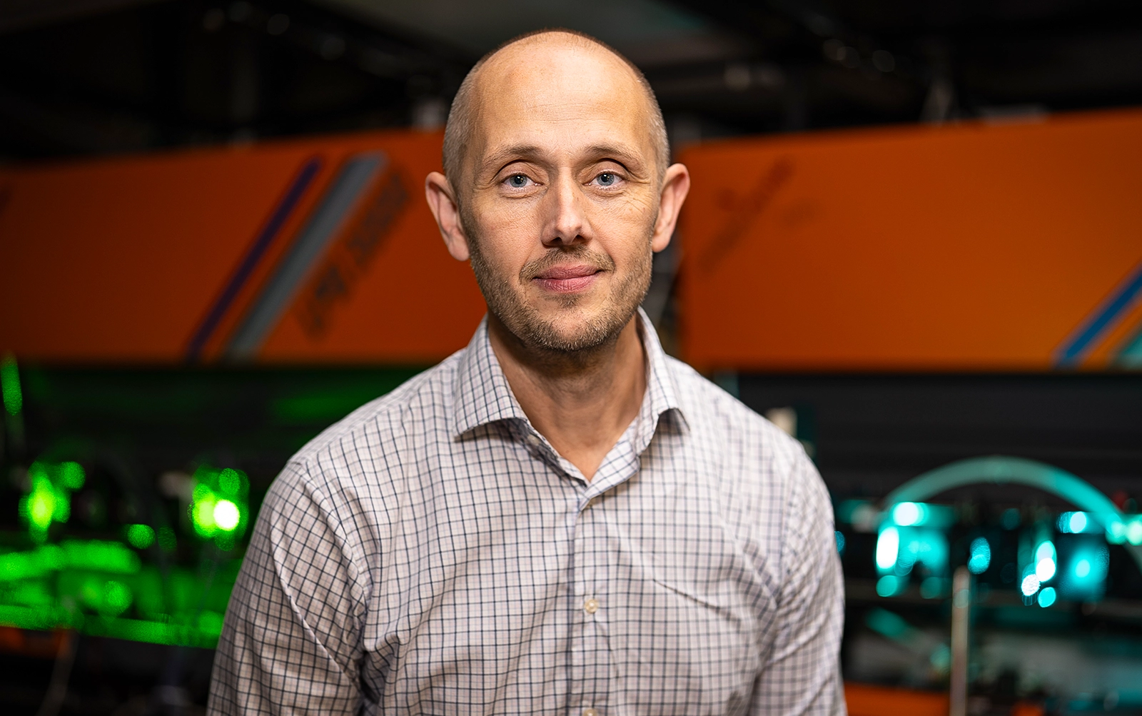 Portrait of a man with green lasers shining behind him.