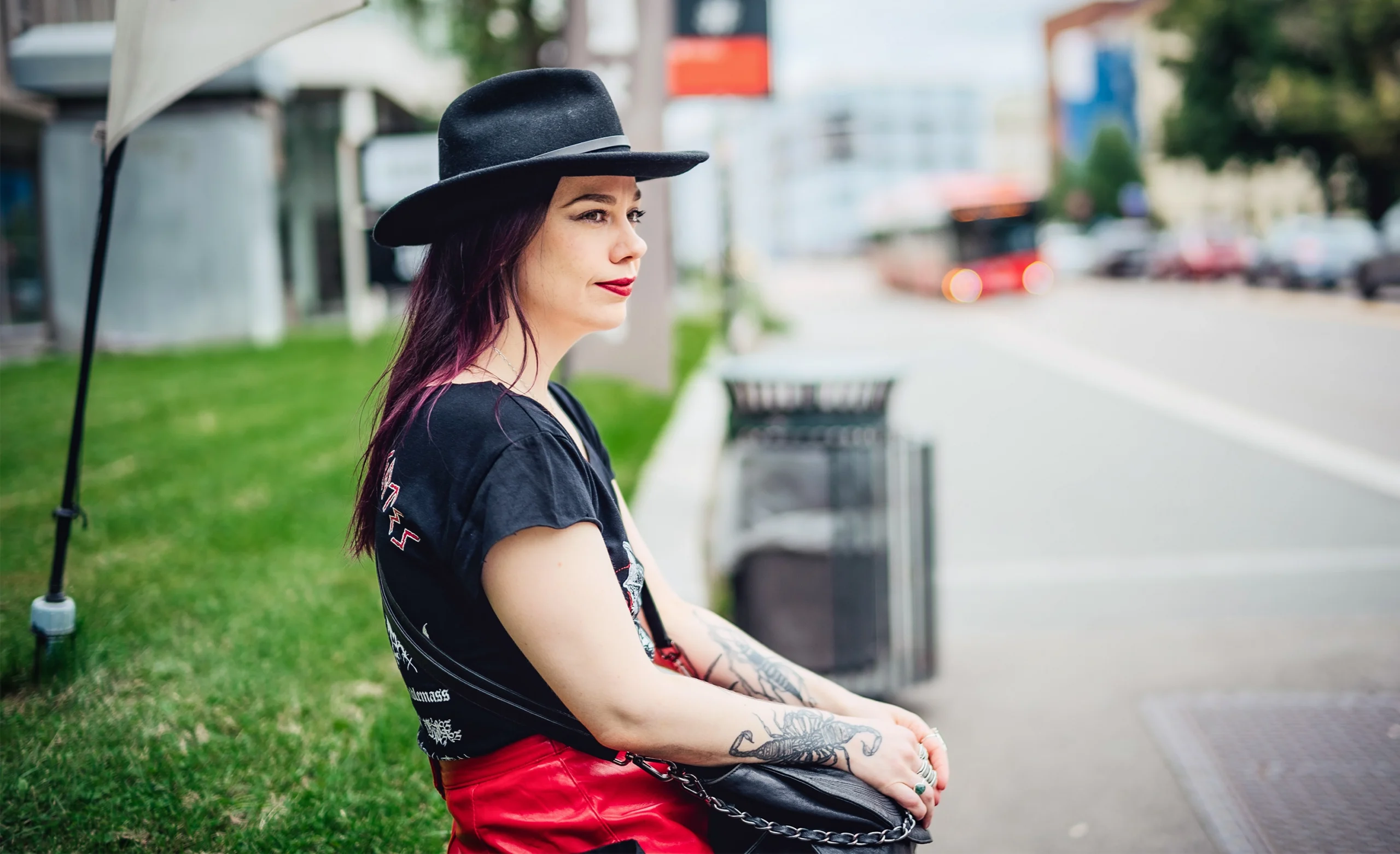 Crowther in a black felt hat sitting at a bus stop.