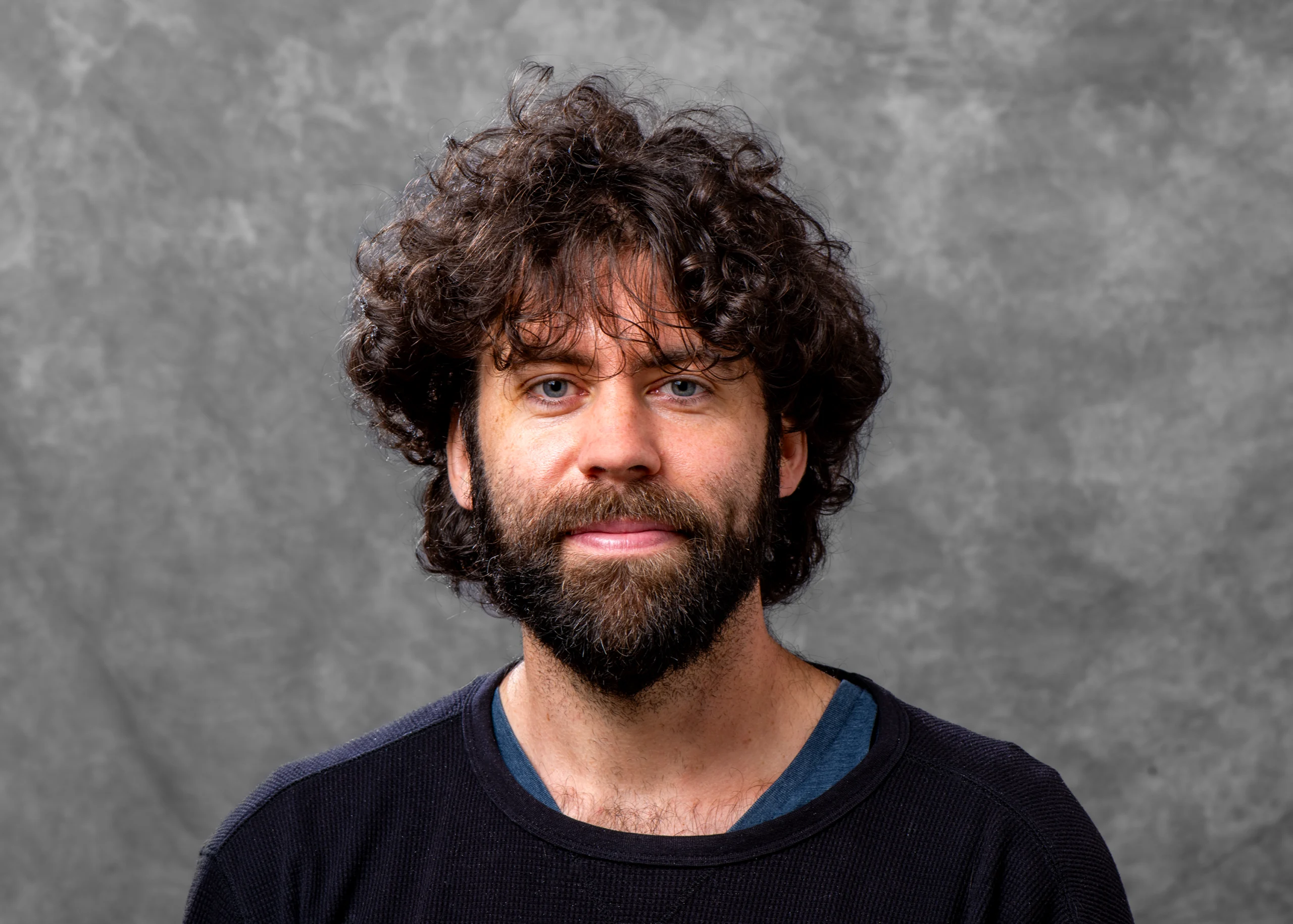 Portrait of a young man with bushy brown hair and a beard.