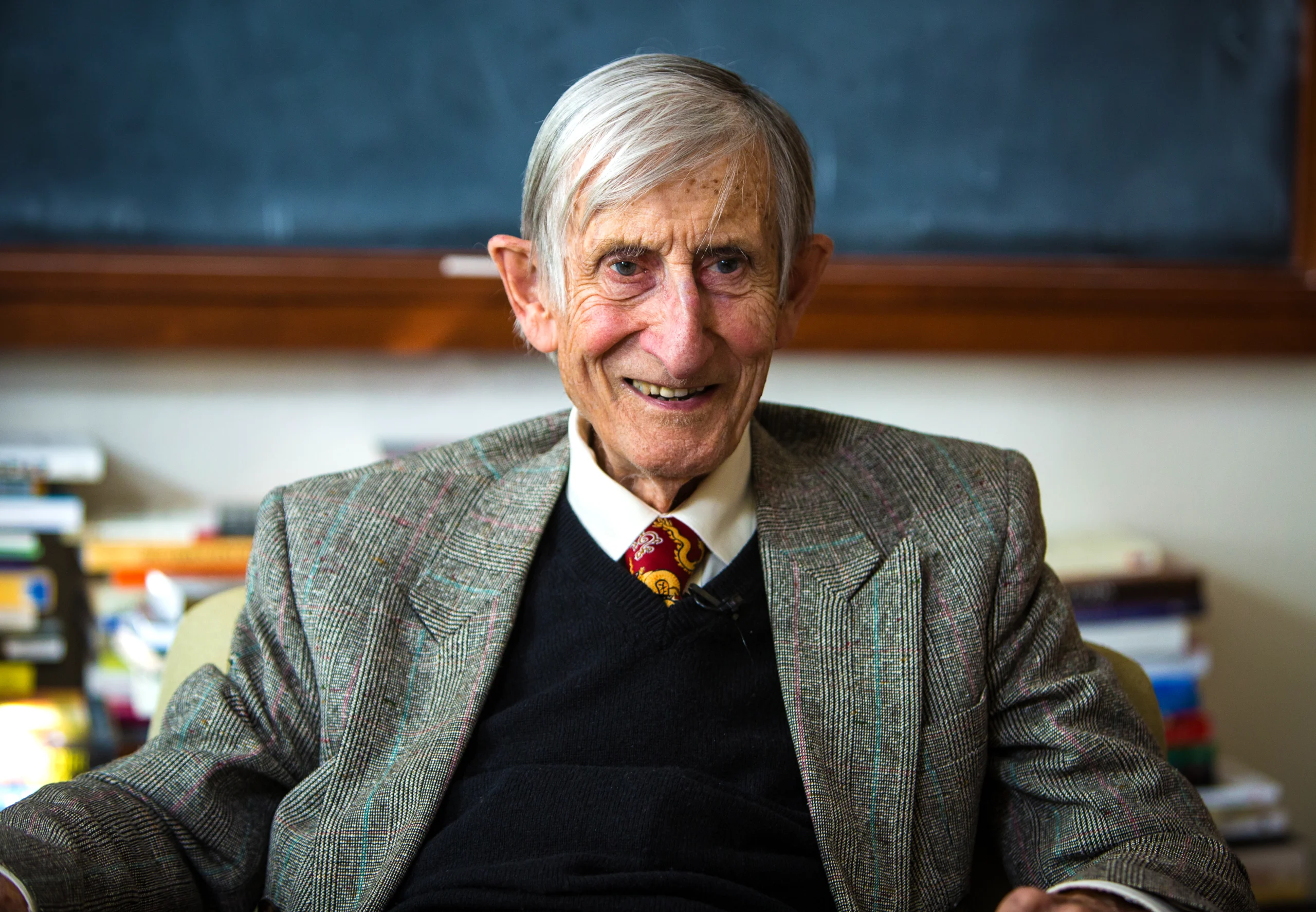 Portrait of a smiling man with gray hair in a tie and wool suit jacket.