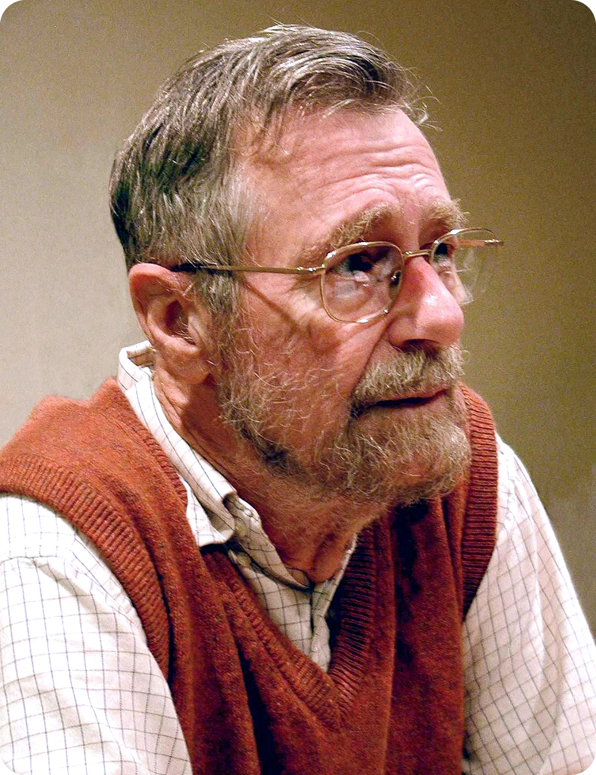 Edsger Dijkstra in a checkered shirt and red vest.