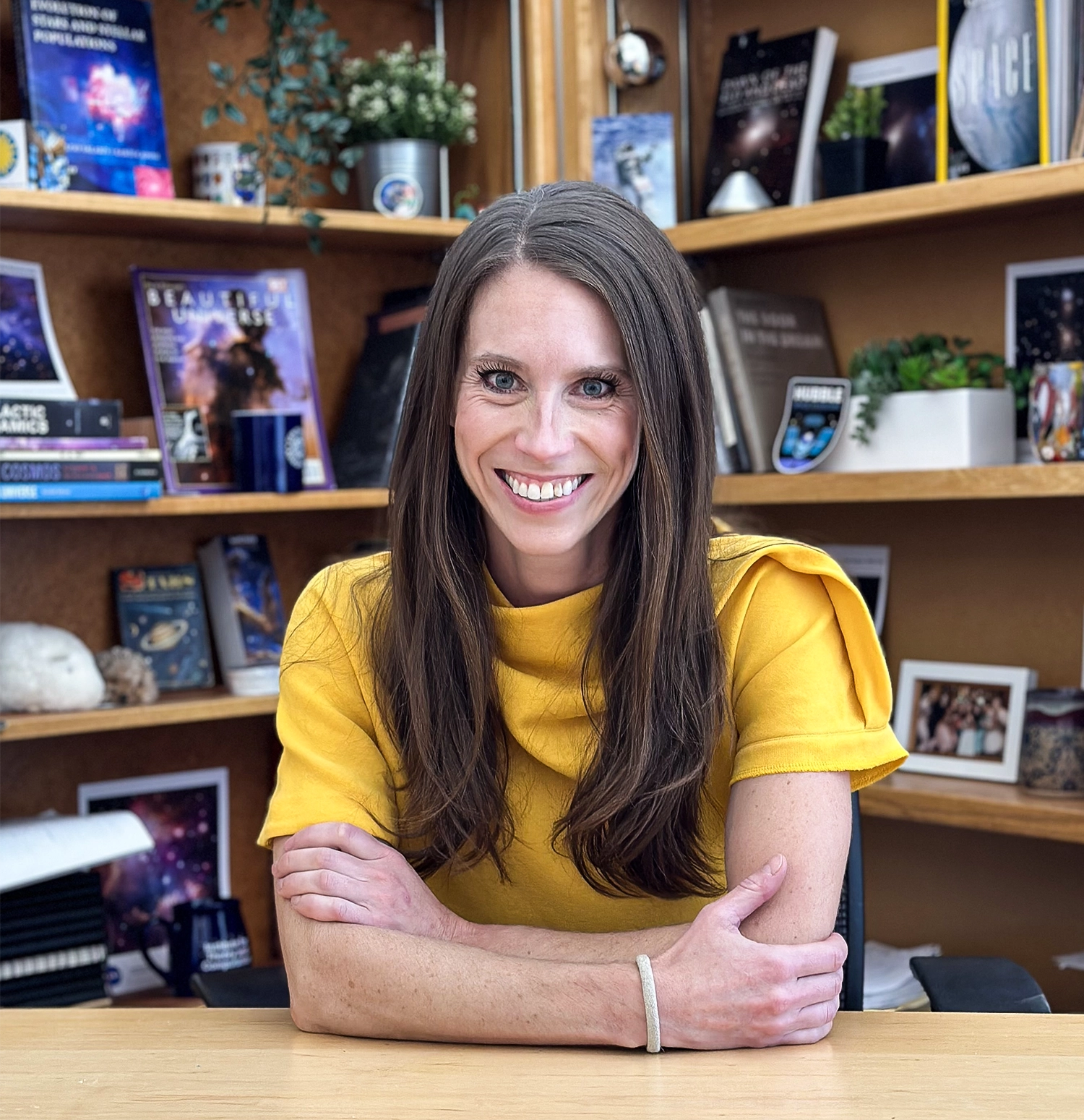 Woman sitting at a table in front of a bookshelf.