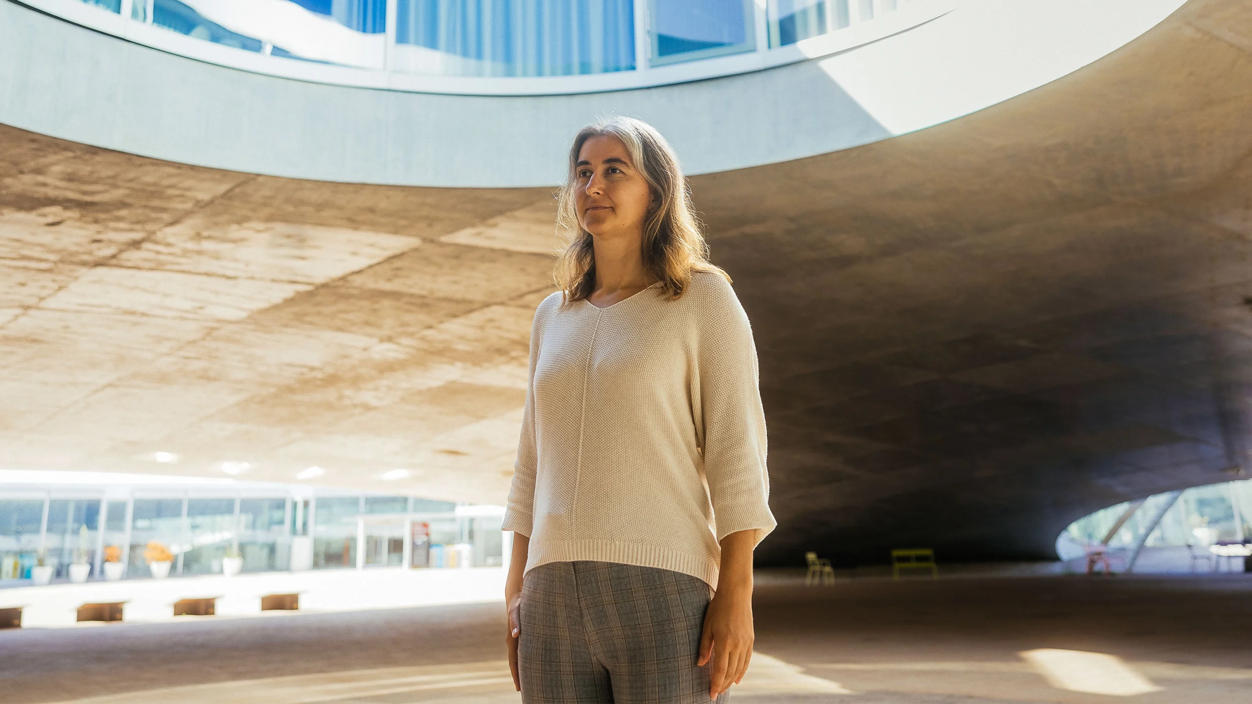 Lenka Zdeborová in a tan sweater stands outside in a large pavilion