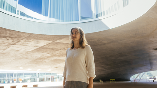 Lenka Zdeborová in a tan sweater stands outside in a large pavilion