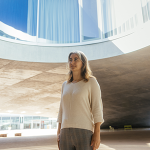 Lenka Zdeborová in a tan sweater stands outside in a large pavilion