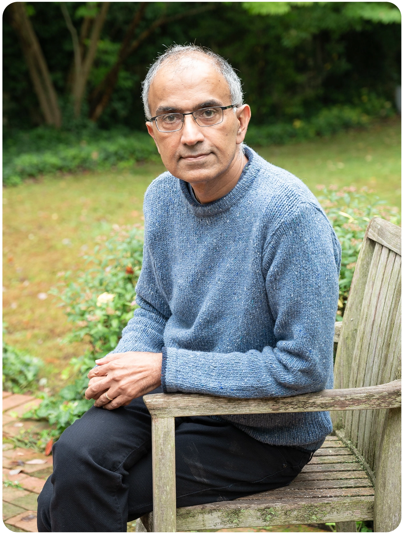 A man in a grey sweater sitting on a bench