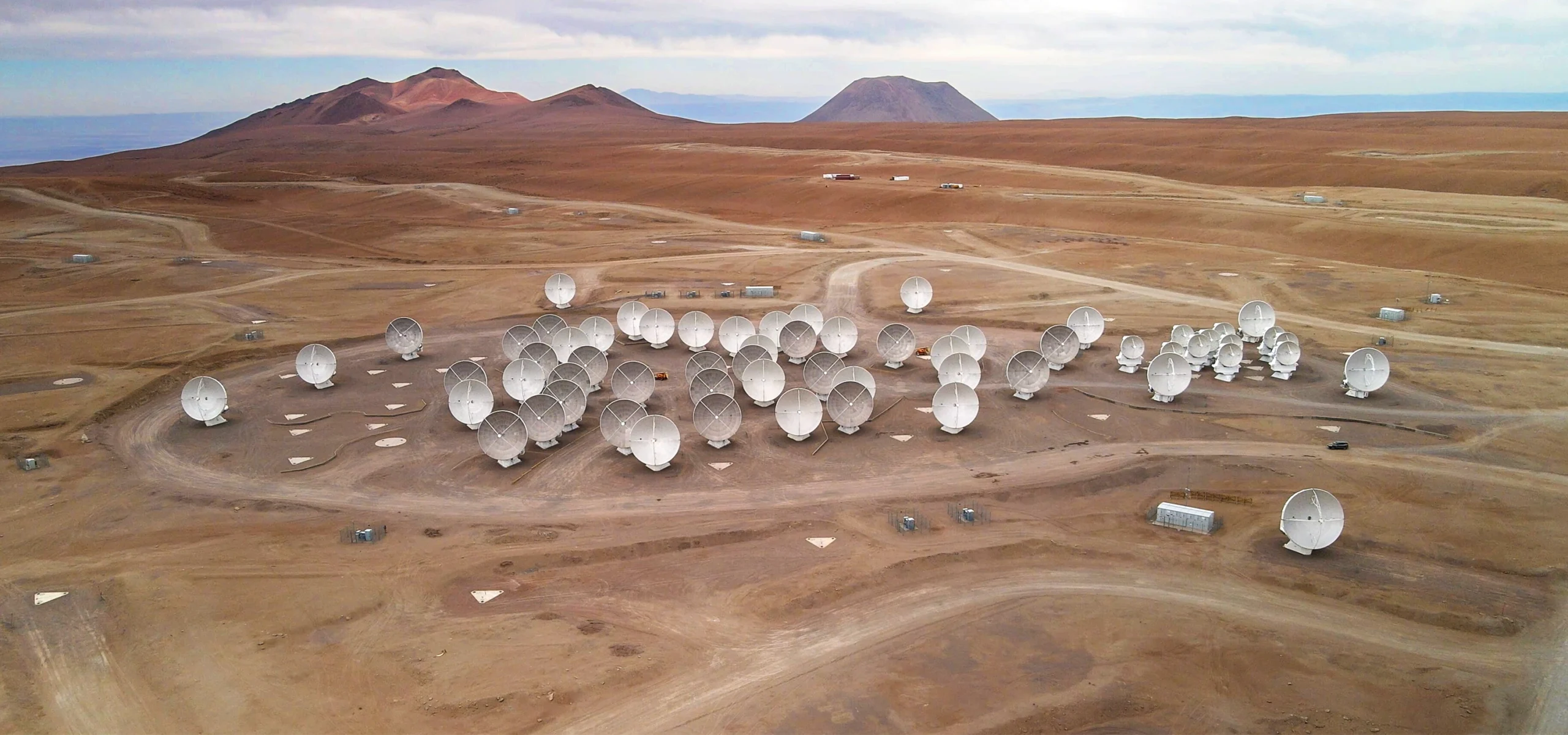 An aerial photo of 66 antenna dishes arrayed across a desert landscape.