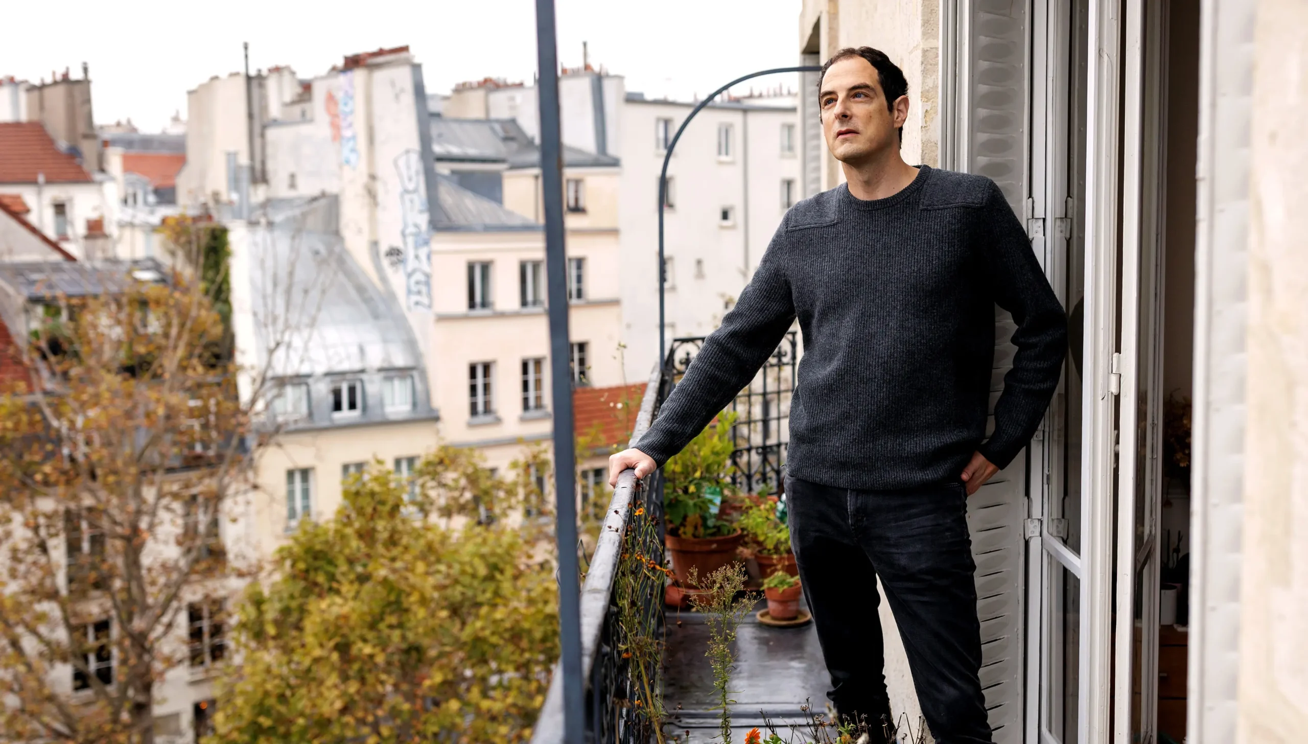 Bessis standing on the balcony of his Paris apartment.