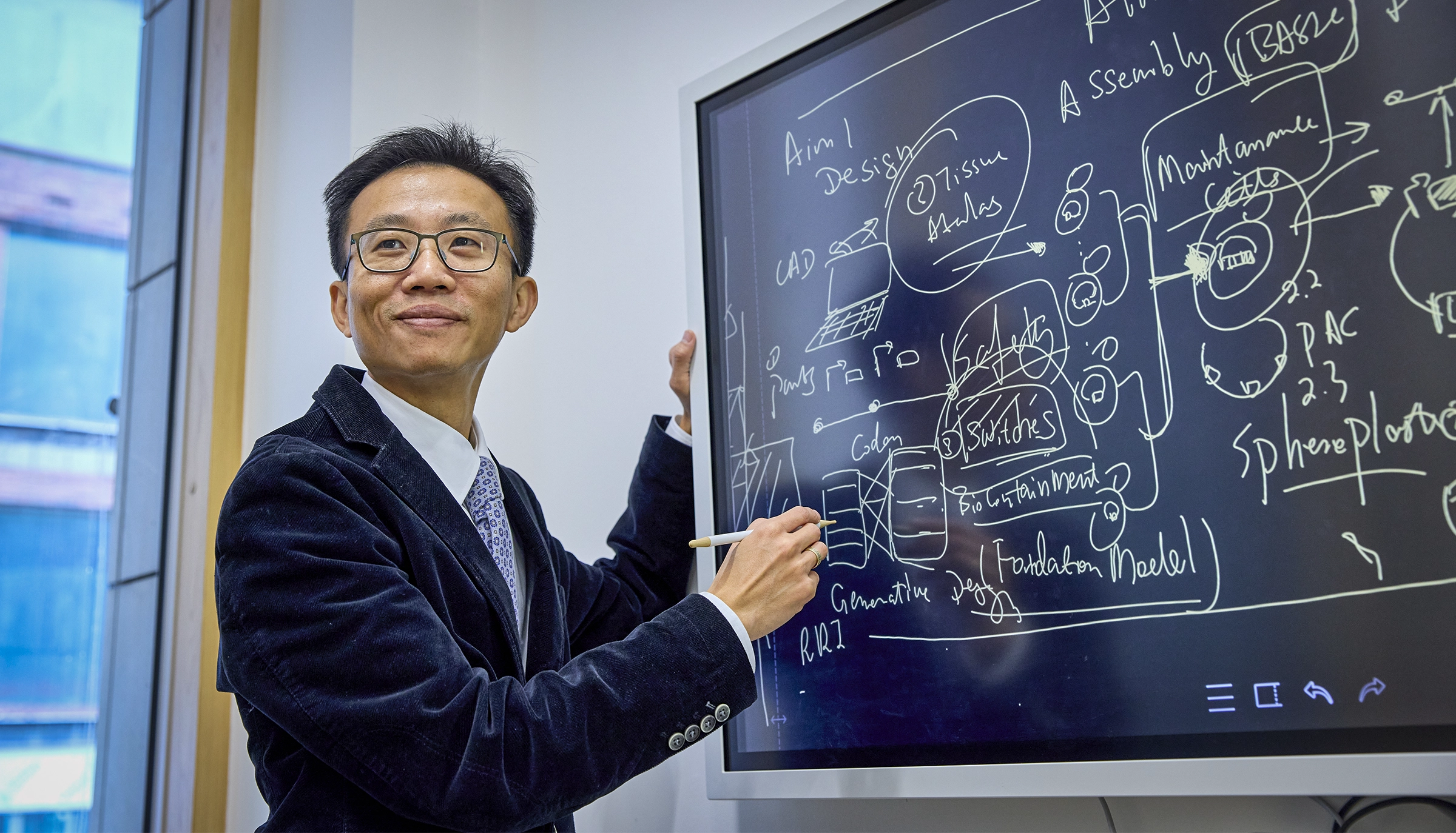 Cai smiles while drawing on a whiteboard