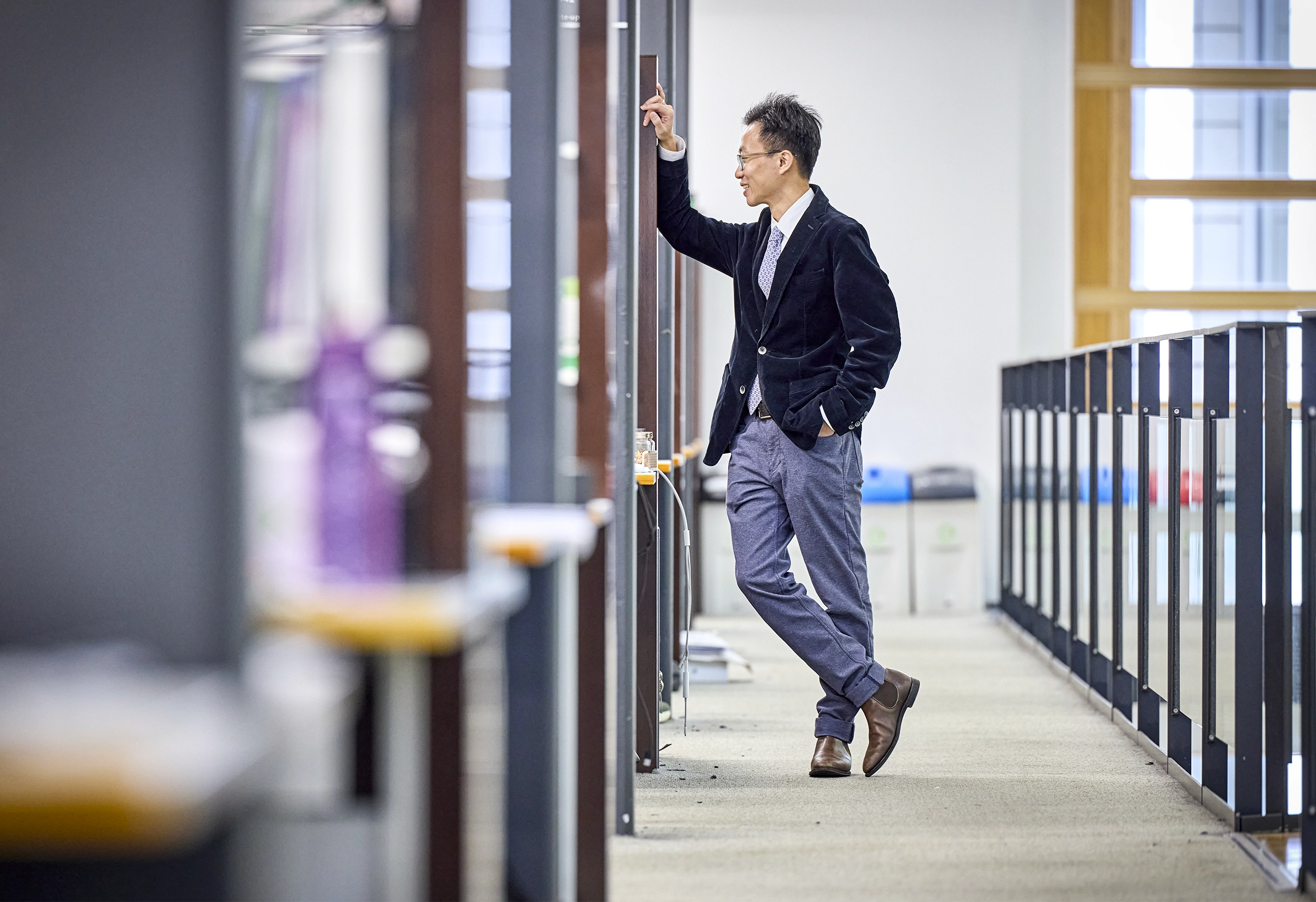 Cai leans on a library stack and looks down the aisle.