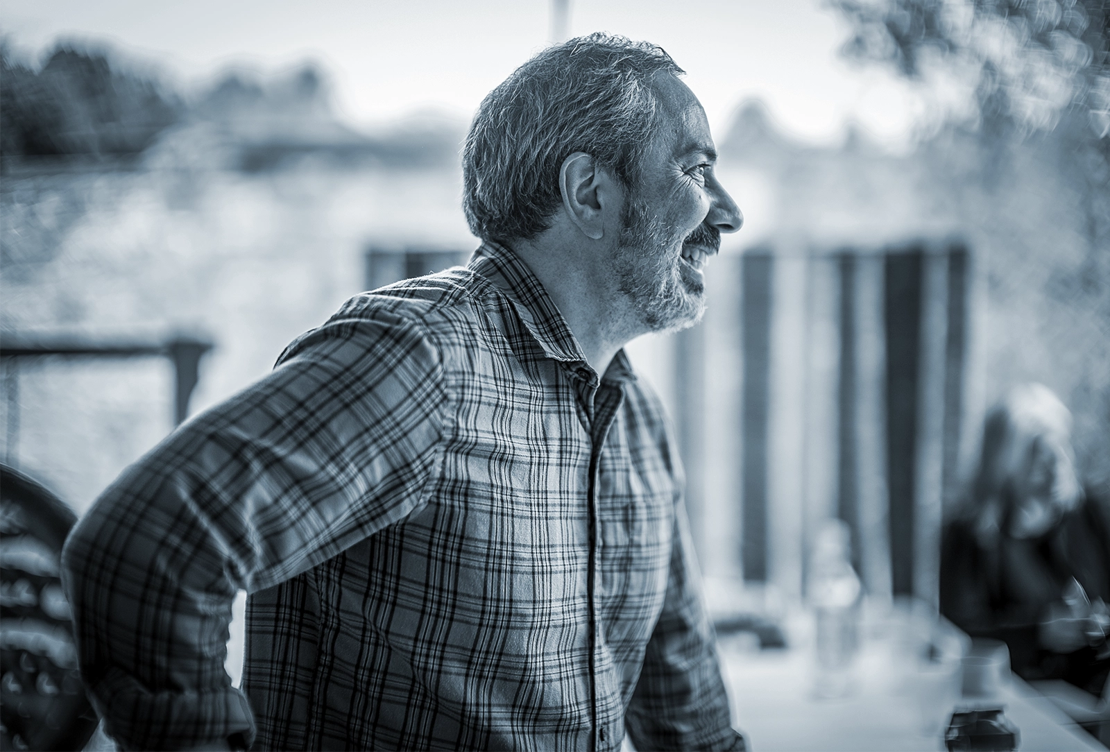 A candid photo of a man in a plaid shirt speaking to someone out of frame.