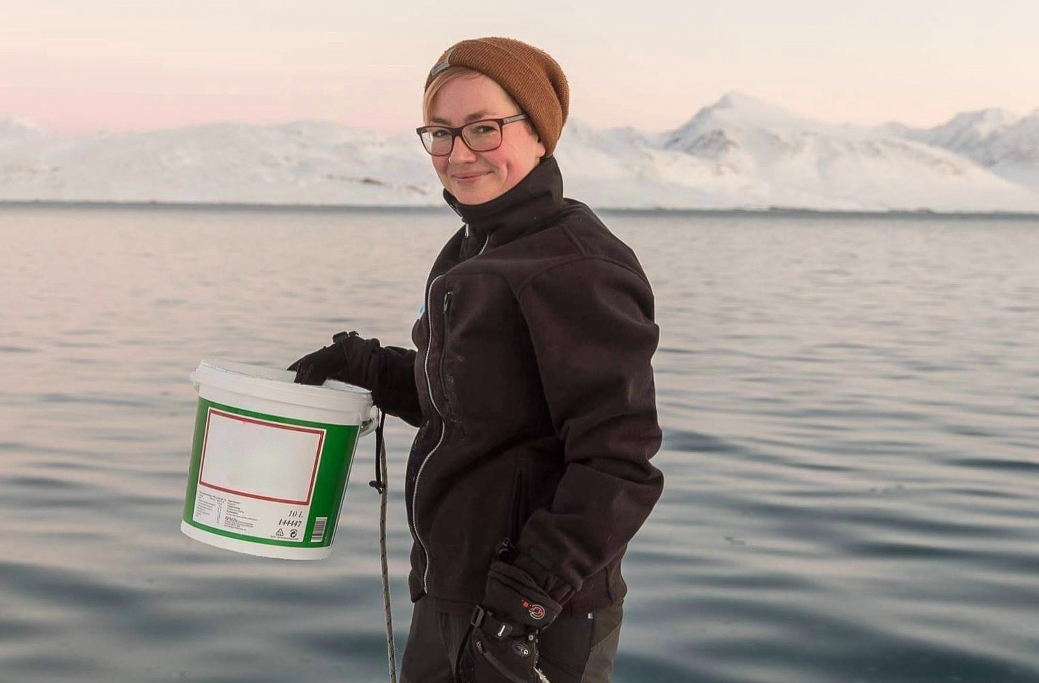 Clara Hoppe holds a bucket in front of icy ocean scenery.