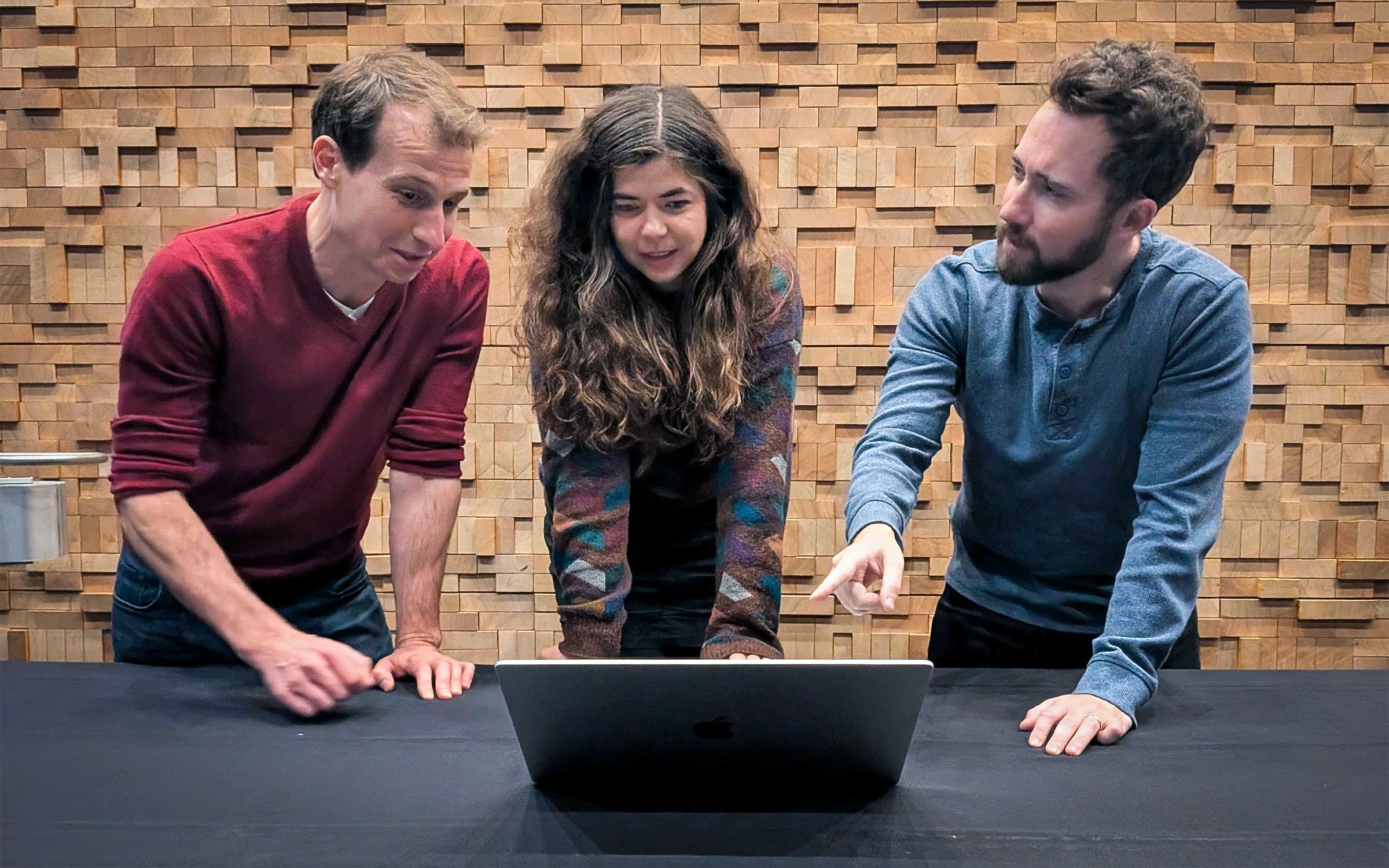 Kyle Mahowald, Isabel Papadimitriou and Richard Futrell look at a laptop on a black surface