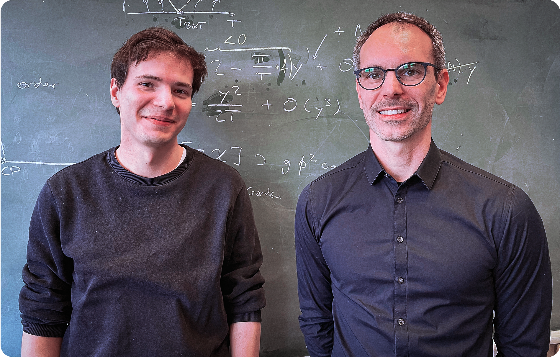 two men standing in front of a blackboard