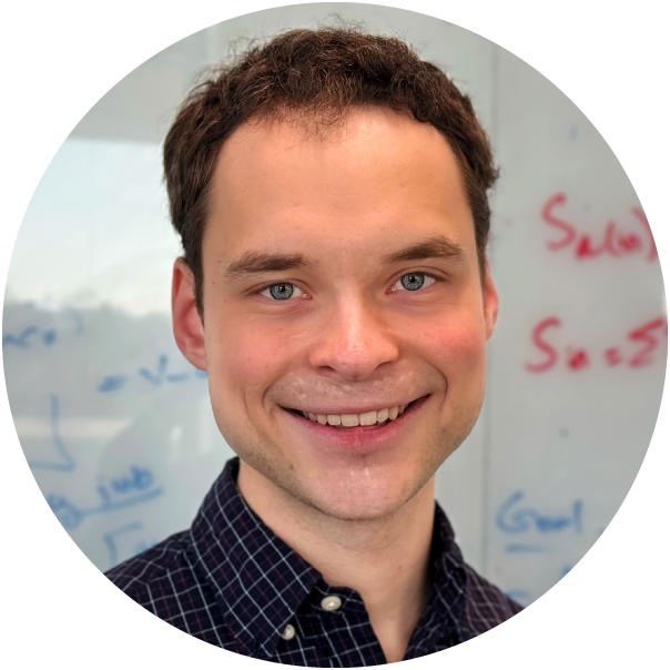 William Kuszmaul in a black checkered shirt in front of a whiteboard.