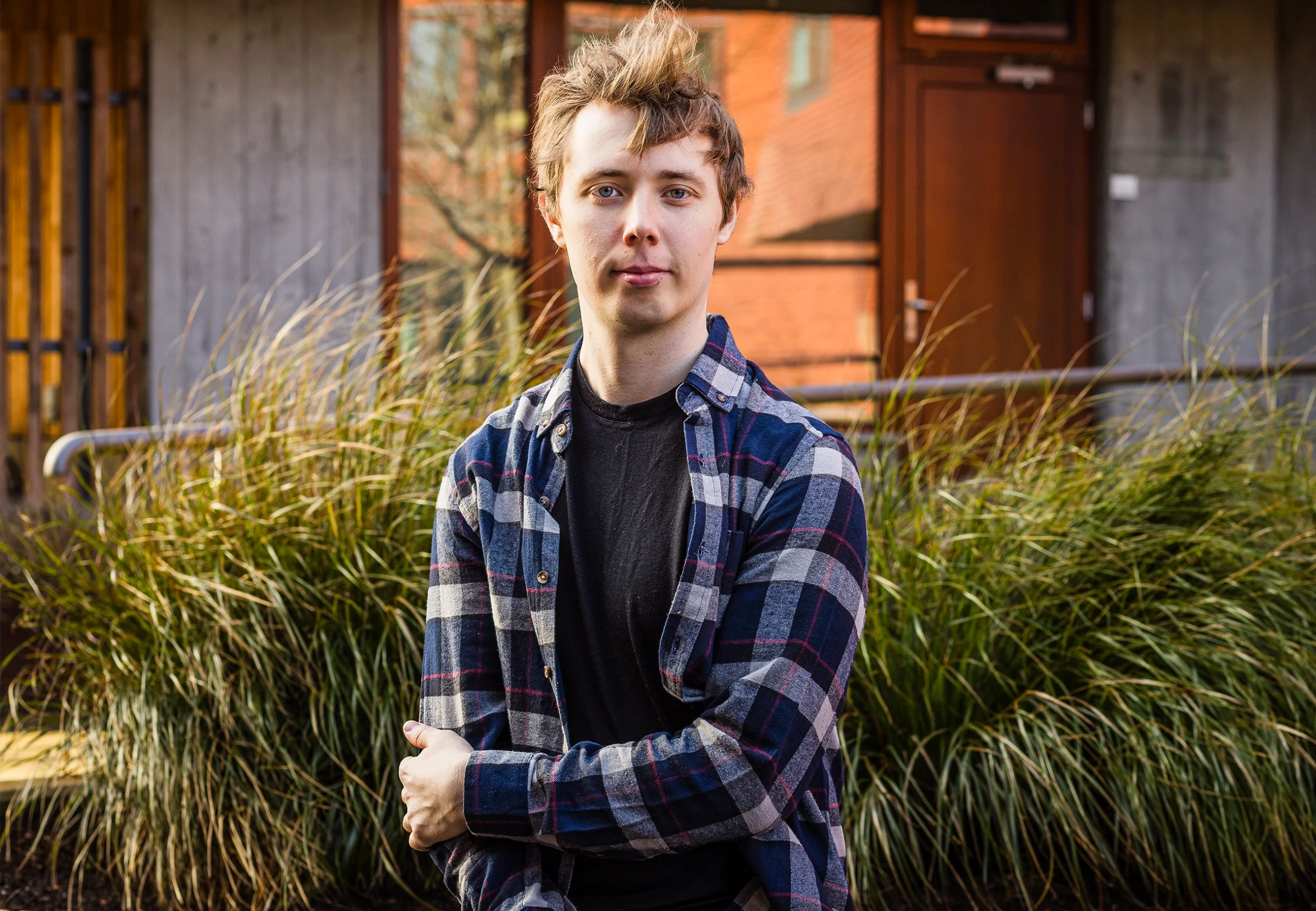 Andrew Krapivin in a black T-shirt and checkered flannel shirt stands outside