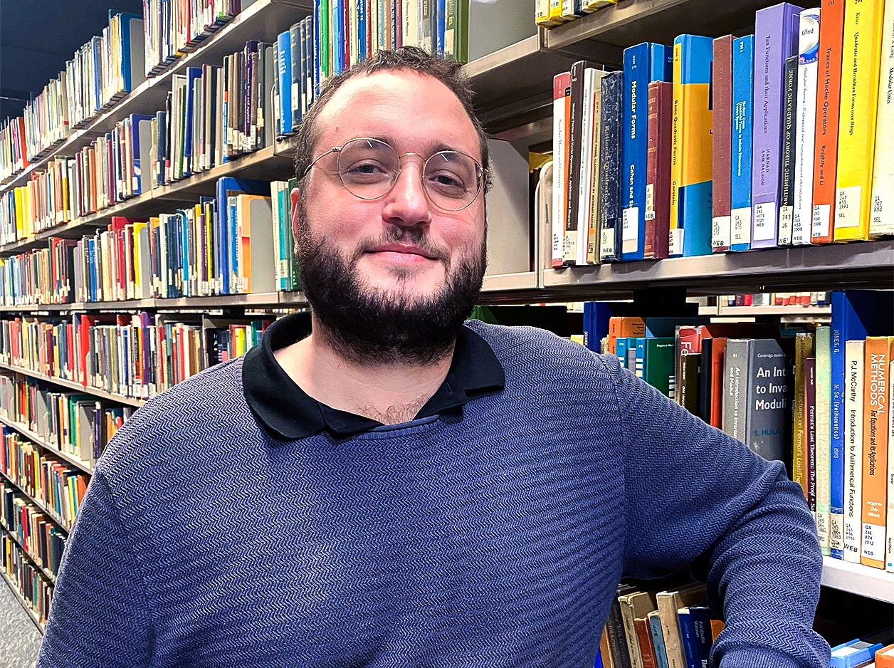 Man with glasses in front of a bookcase.