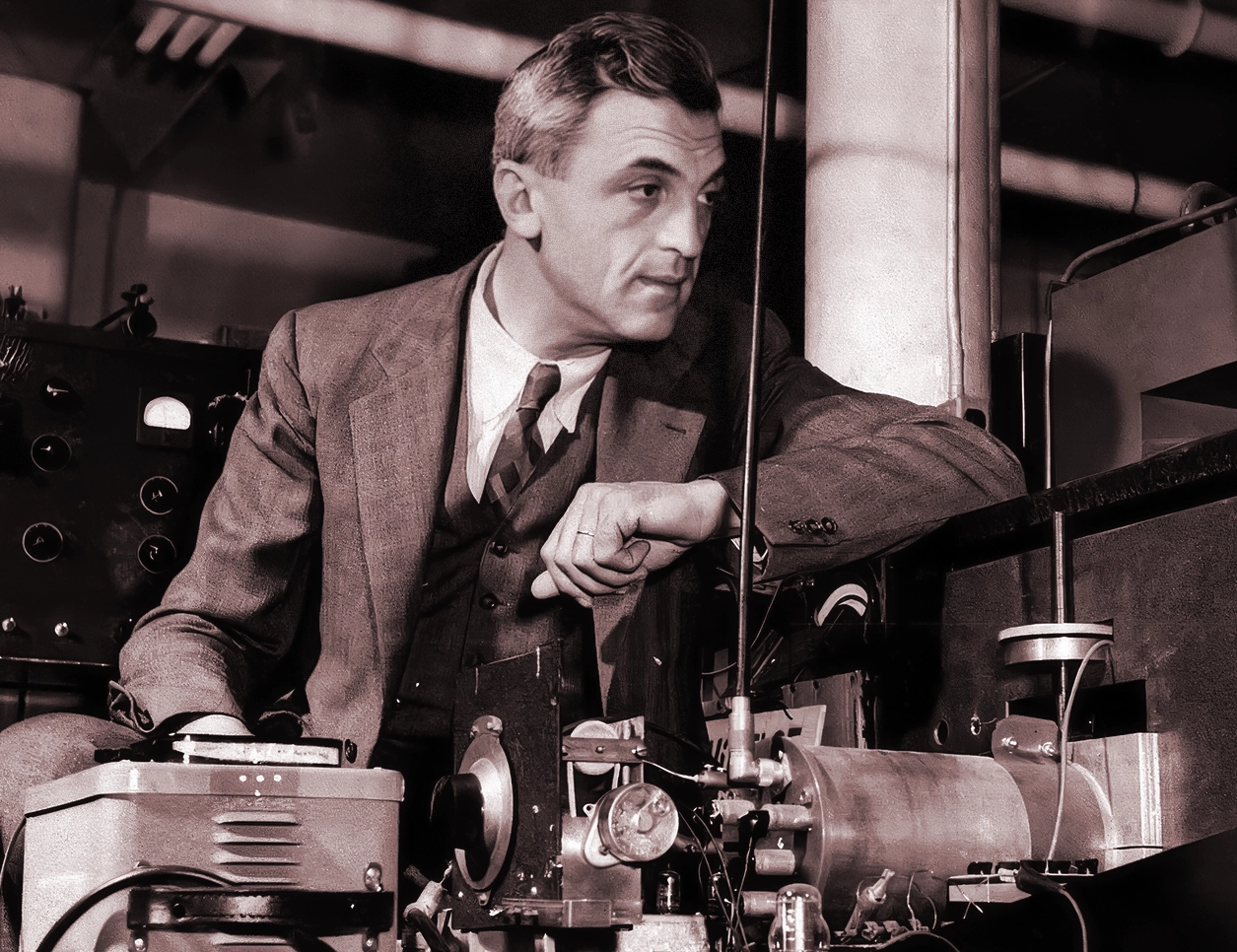 A man wearing a suit leans over an experimental apparatus.