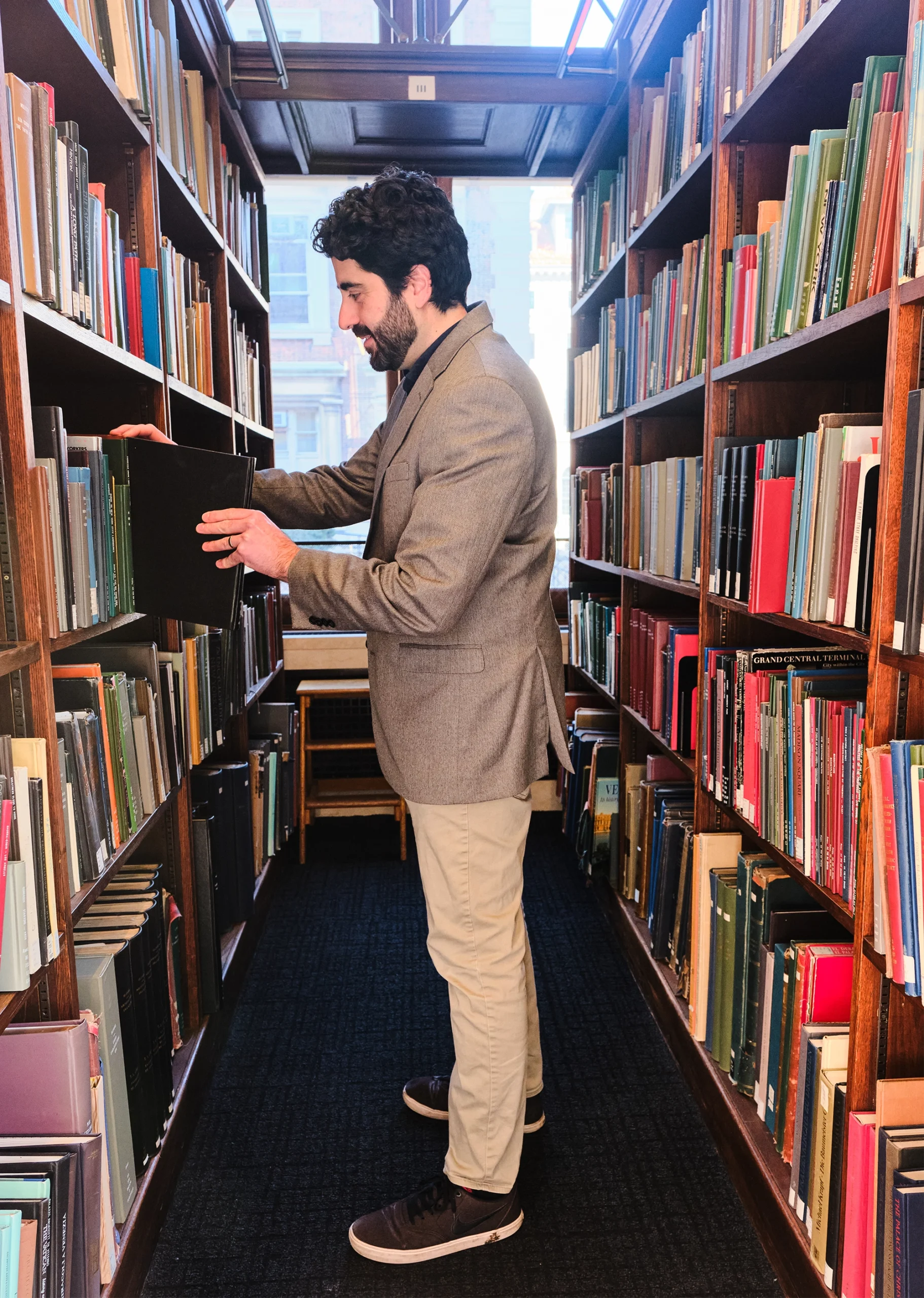 Christopher Baldassano stands in the stacks of a library.