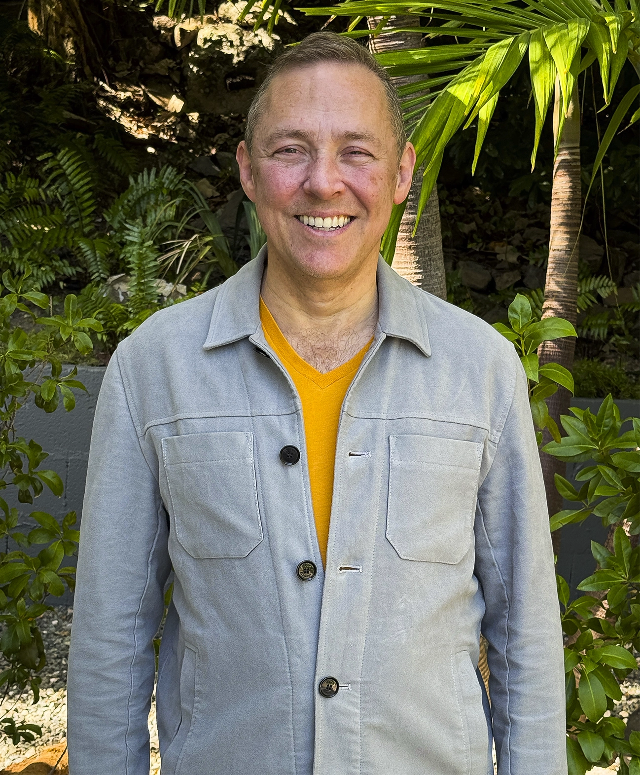 Martín Farach-Colton in a gray shirt stands in front of green plants