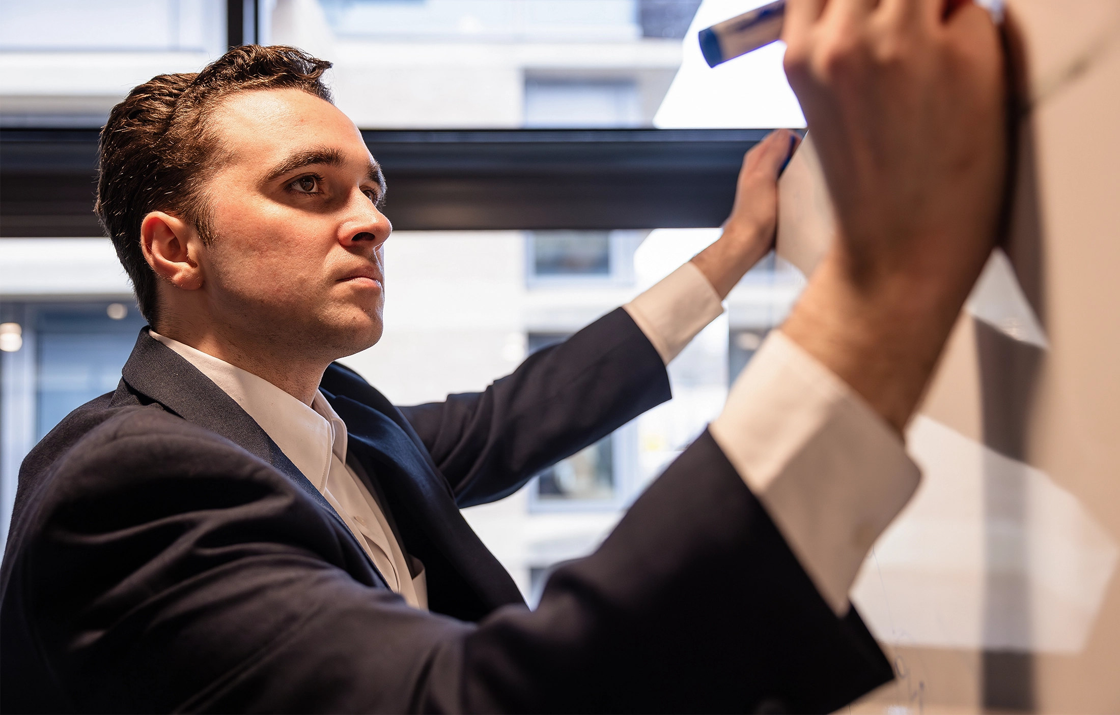 Miles Cranmer in a blue blazer writes on a whiteboard