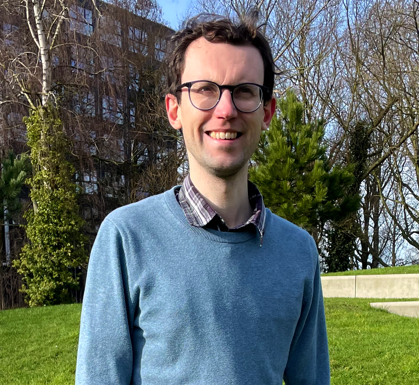 Man in a blue sweater standing outside.