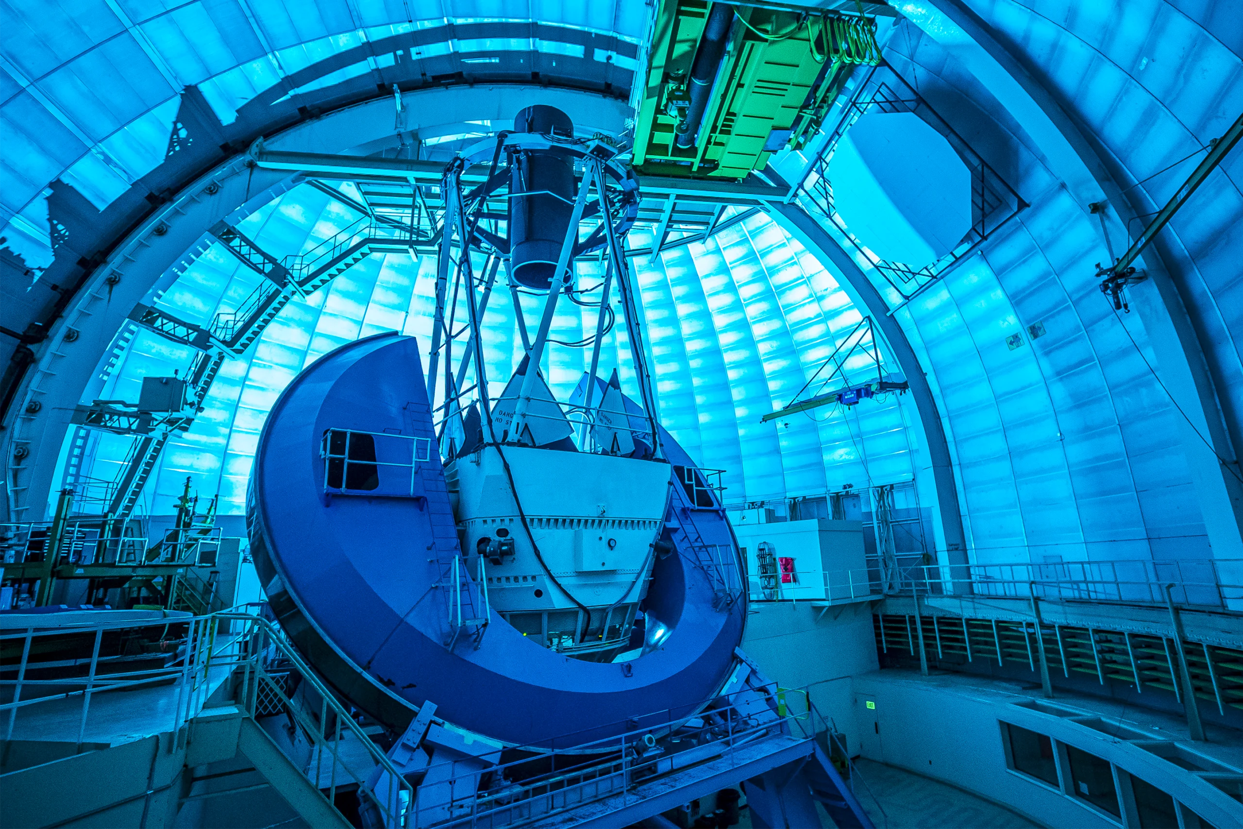 A photo of the interior of a telescope, with a black cylinder pointing up at the telescope’s closed dome.