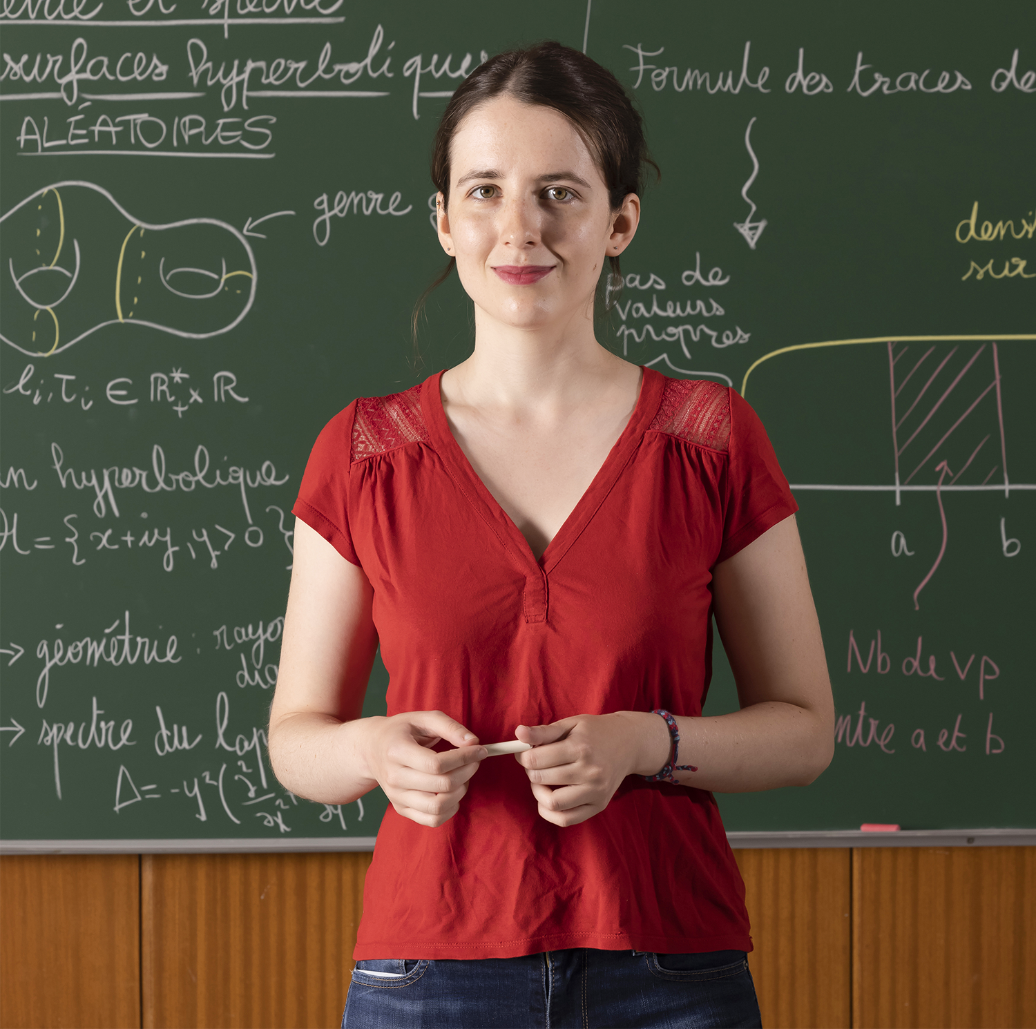 Woman in front of a blackboard, smiling.