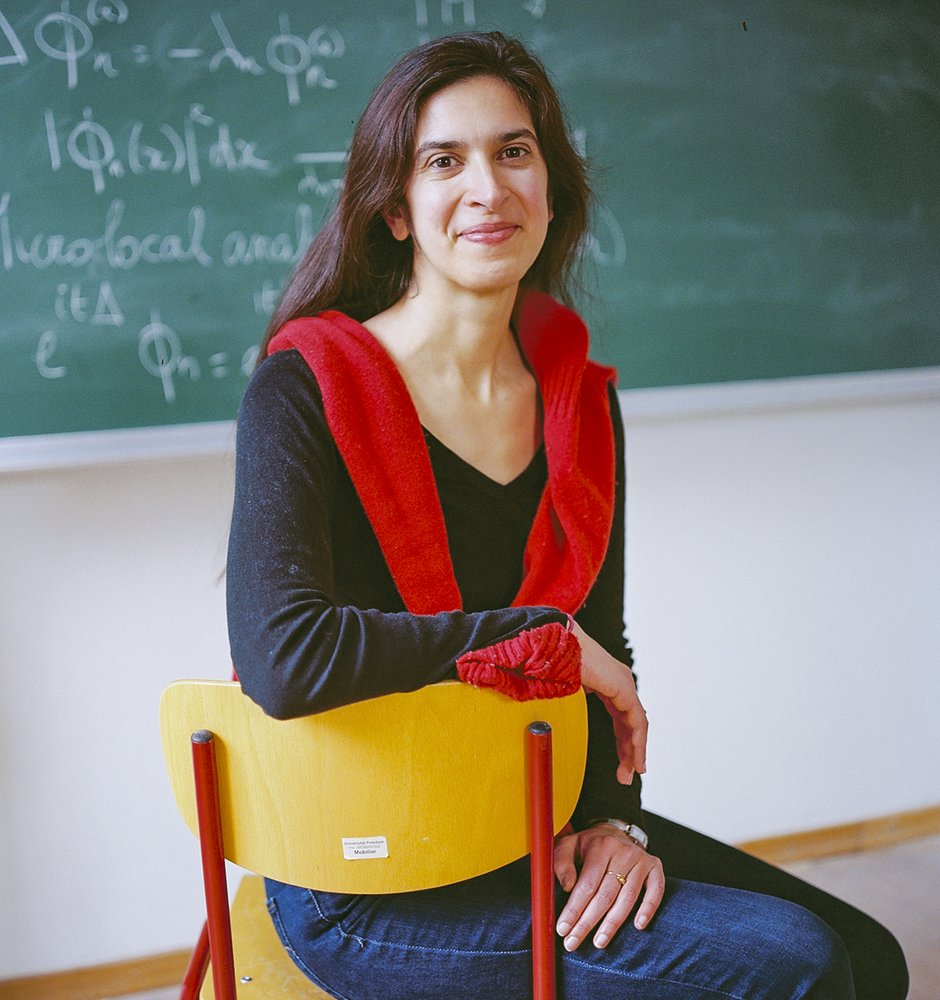 Woman in front of a blackboard, smiling.