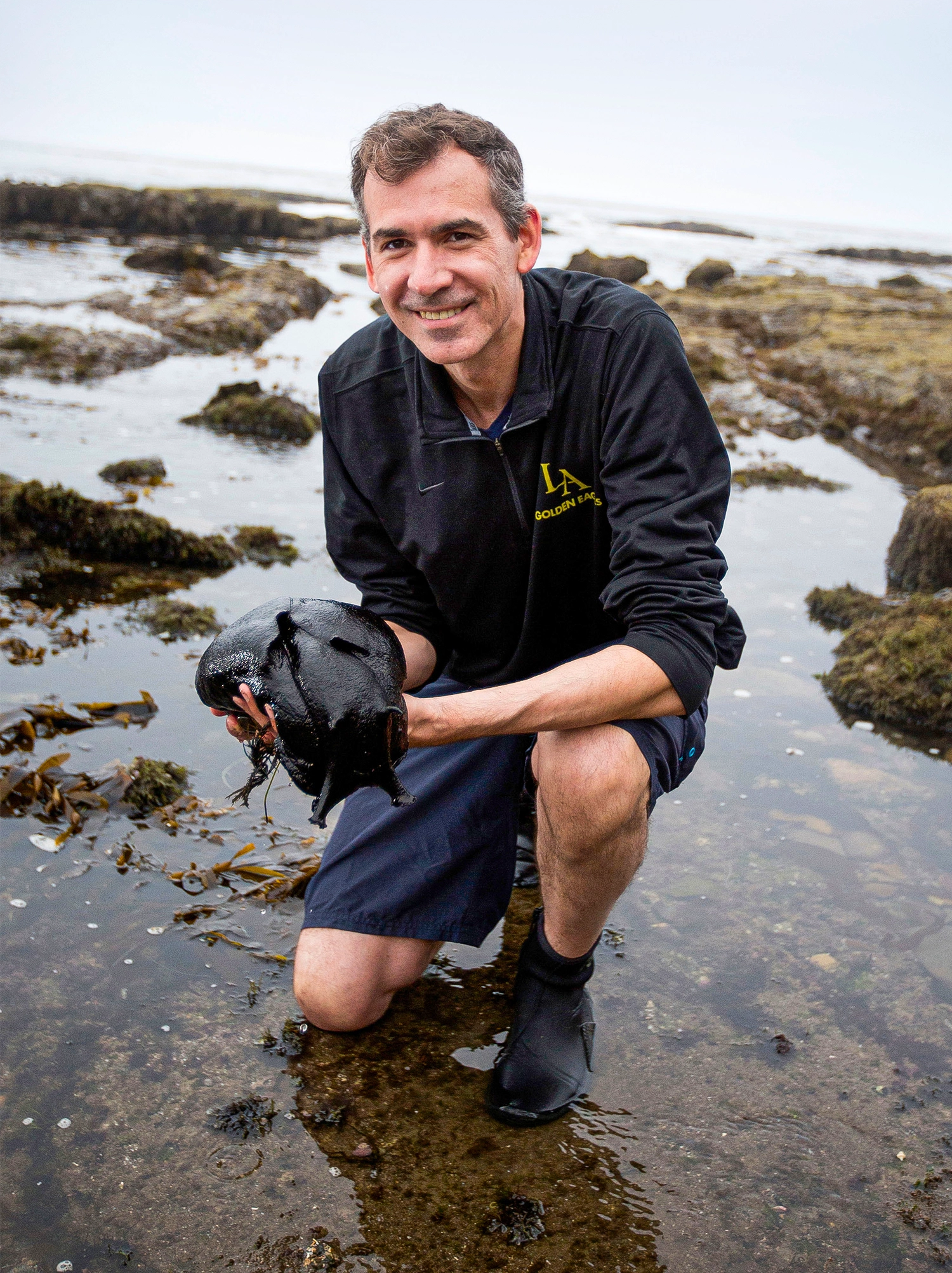 A portrait of Patrick Krug holding the world's largest gastropud mollusk.