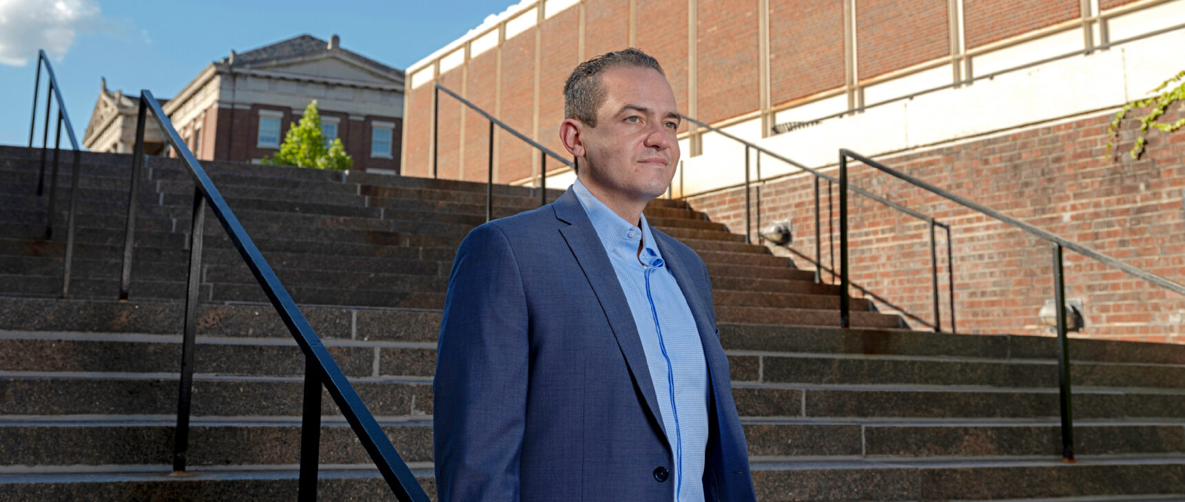 A man in a blue suit walking down the stairs outdoors.