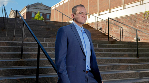 A man in a blue suit walking down the stairs outdoors.